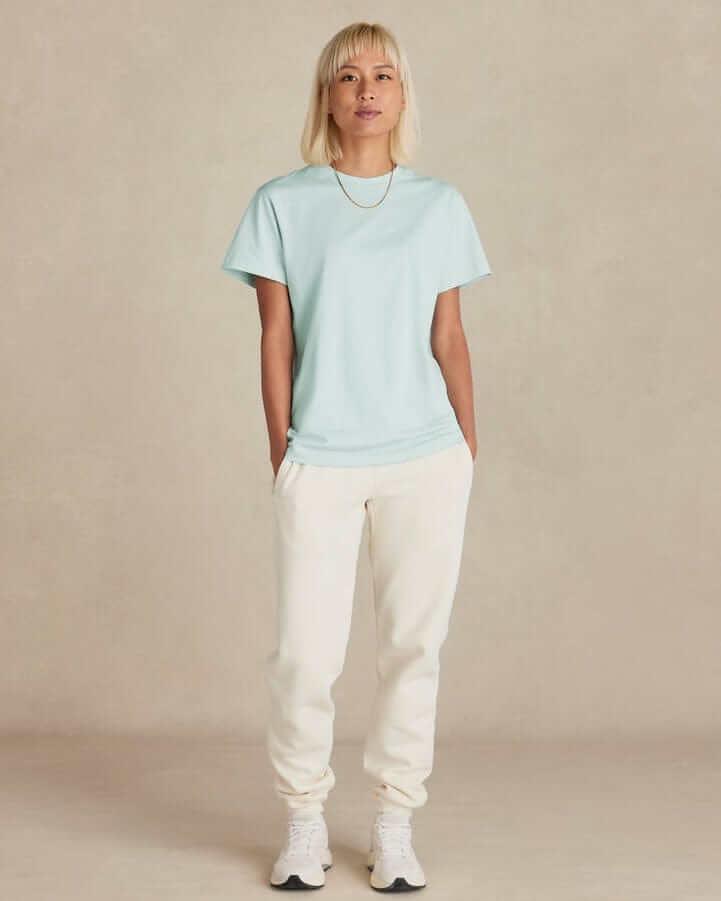 Woman wearing organic cotton sweatpants midweight in cream with a light blue t-shirt and sneakers